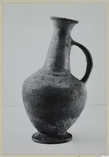 Pottery Base-Ring Ware jug with a flared neck, single loop handle and foot ring, shown against a plain backdrop