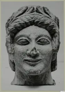 Limestone head of a bust with curled hair and a smiling face, from Mersinaki