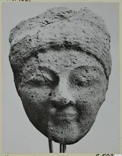 Terracotta head from Mersinaki with a close-fitting cap, cracked down the left cheek and broken at the top