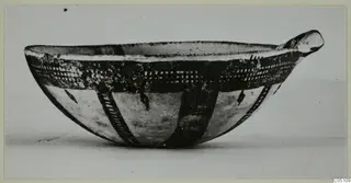 Pottery White Slip Ware bowl with dark painted bands and a small lug at one side, seen from the side