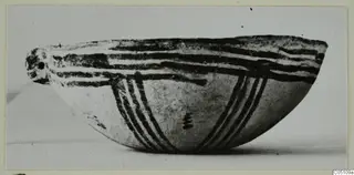 Side view of a White Slip Ware bowl with dark painted bands and stripes on its outside