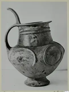 Pottery tankard with a high loop handle, rope-moulded bands at the neck and round applied discs on the body.