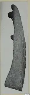 Curved iron tool with two knob-like projections on one edge, photographed against a pale background