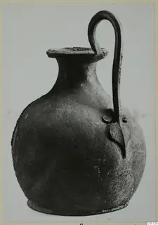 Round-bodied jug with a tall looped handle and a flat rim, photographed against a plain background.