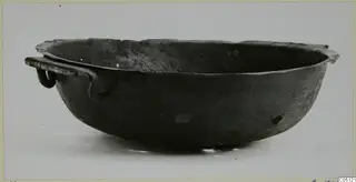 Shallow bowl with a flared rim and a ring-ended strap handle, shown in side view