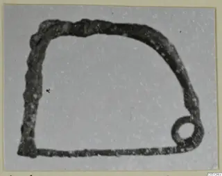Find from the Kastros tombs at Lapithos: a dark metal loop with a small ring at one lower corner.