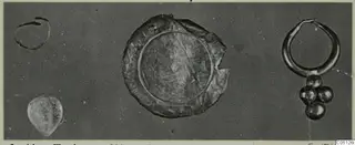 Small finds on a dark ground: an open ring, a pale pear-shaped object, a flat circular disc and a ring with a bead cluster