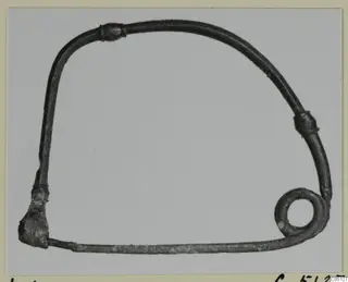 Bent metal wire object, dark and corroded, forming an open rounded frame with a closed loop at lower right