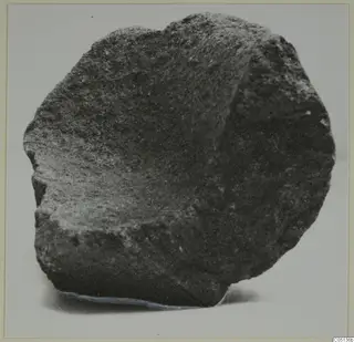 Fragment of a stone mortar from Petra tou Limniti, shown from the side against a pale background