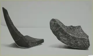Two broken curved stone fragments from Petra tou Limniti on a pale surface