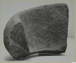 Fragment of stone from Petra tou Limniti, shown on a plain background with a rounded outer face and a flatter dressed face.