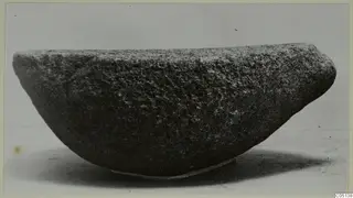 Rough stone bowl from Petra tou Limniti, photographed on a thin support against a plain grey backdrop.