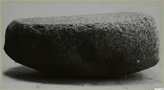 Stone object from Petra tou Limniti, an elongated block with rounded ends, photographed on a pale surface.