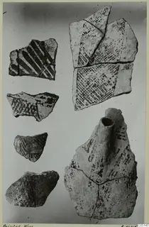 Painted pottery sherds laid out on a pale background, one fragment with a short tubular spout.