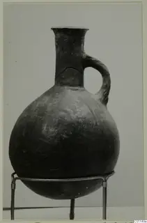 Red Polished III jug with a single loop handle, shown on a wire stand against a plain grey background.