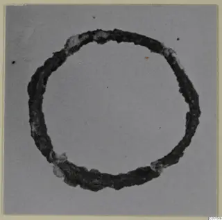 Corroded bronze ring, a personal adornment from Lapithos, photographed on a plain grey background