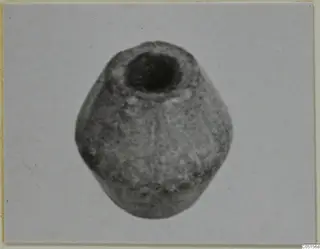 Stone object with a wide circular opening at the top, photographed alone against a pale background.
