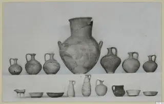 Two rows of pottery vessels from Kountoura Trachonia, Tomb 3: a large two-handled jar with jugs and bowls around it