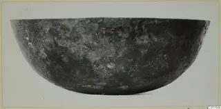 Dark, mottled bowl photographed in side view, a find from the Kastros tombs at Lapithos