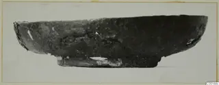 Side view of a dark, shallow bowl with a short foot, from the Kastros tombs at Lapithos