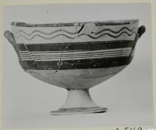 Footed bowl with two small side handles and painted dark wavy lines and bands, photographed on a mounted print.