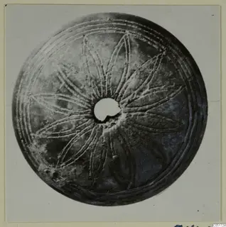 Round bone disc with a central hole and incised radiating petal-like pattern, from the Kastros tombs at Lapithos