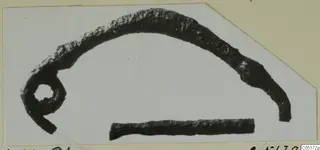 Corroded bronze loop with a curved arm, and a separate short bronze rod, from the Lapithos Kastros tombs finds