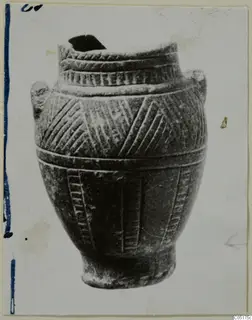 Jar with incised chevron and hatched bands and two lug handles, photographed against a plain light background.