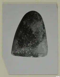 Single dark, mottled object with a rounded top and broad base, photographed on a mounted card, from Ayios Iakovos