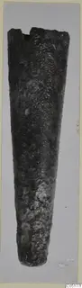 Heavily corroded metal object tapering to a broken, uneven rim at the top, shown upright.