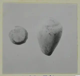 Two small finds photographed on a grey background: a flat-topped disc-shaped object and a larger cone-shaped object