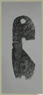 Flat corroded metal object in two broken pieces, with a round hole near the top, from Ayios Iakovos