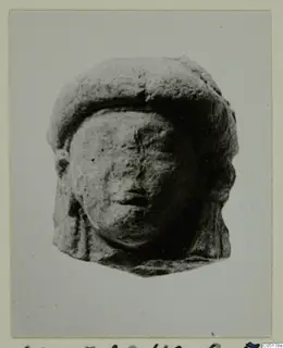 Small terracotta head of a figure with a flat cap, photographed on a mounted card