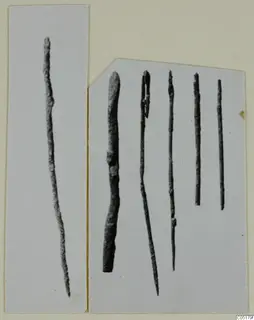 Six slender metal rods on mounted cards, from Ayios Iakovos Tomb 8, shown in a photograph.