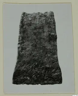 Corroded metal object, broad at the base and narrowing toward a broken top, from Ayios Iakovos Tomb 8.