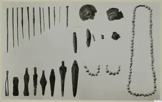 Bronze tools and small finds from Ayios Iakovos laid out on a pale board: pins, tanged blades, beads and discs.