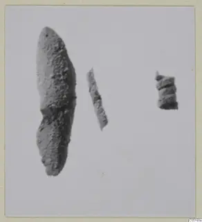 Three small corroded metal objects: a leaf-shaped piece, a thin strip and a short coiled piece, on a pale ground