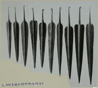Row of metal weapon blades with looped tangs, photographed on a card mount, from Lapithos