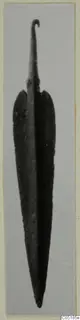 Long leaf-shaped bronze blade with a curled tang, from Lapithos Tomb 320, against a grey background