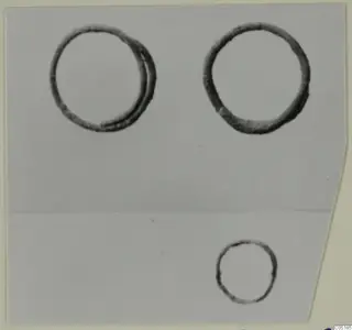Three dark metal rings photographed on a grey background, two larger rings at the top and one small ring lower right.