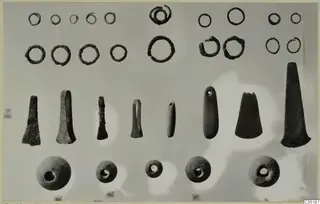 Metal rings, blade-like objects and round beads from Lapithos Tomb 316, arranged in rows on a pale backdrop