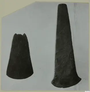 Two dark, tapered metal objects photographed side by side on a pale grey ground, one short and one long