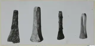 Four metal objects from Lapithos Tomb 316 laid in a row against a grey background