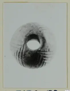 Small find from Lapithos Tomb 313 A: a rounded object with a large central hole and incised grooves