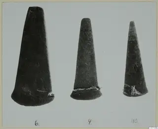 Three tapering dark objects standing in a row, numbered 6, 4 and 110, from Lapithos Tomb 313A