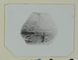 Small rounded grey object with dark incised lines, from Lapithos Tomb 313 A, shown on a card mount