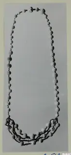 Necklace of pale spherical beads and small spacers laid out in a long loop, from Lapithos Tomb 313 B
