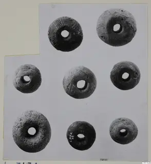 Seven perforated round objects, some with incised lines, from Lapithos Tomb 315 A, arranged on a mounted card