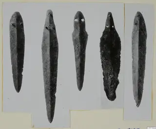 Five bronze blades with rivet holes at their broad ends, from Lapithos Tomb 315, shown on a mount card.