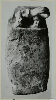 Tall vessel with a loop handle and incised herringbone decoration, photographed alone against a plain background.